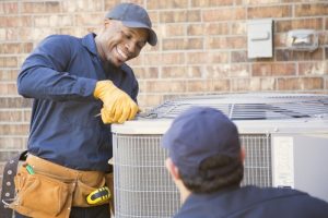 smiling-HVAC-technician-working-on-a-heat-pump